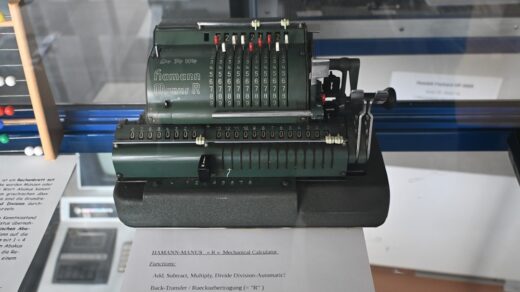 Antique dark green mechanical calculating machine on display