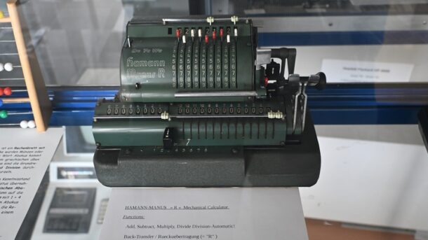 Antique dark green mechanical calculating machine on display