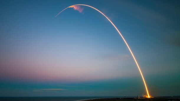 Rocket launch leaving a bright light trail at dusk, evoking the 1977 Voyager 2 liftoff